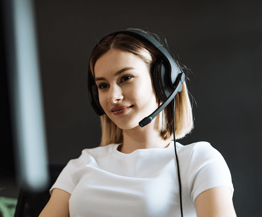 Young professional woman working in call centre on desktop pc with headphones
