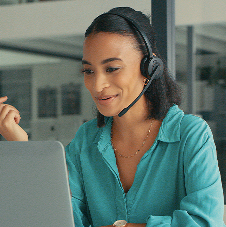 Shot of a young woman using a headset and laptop in a modern office