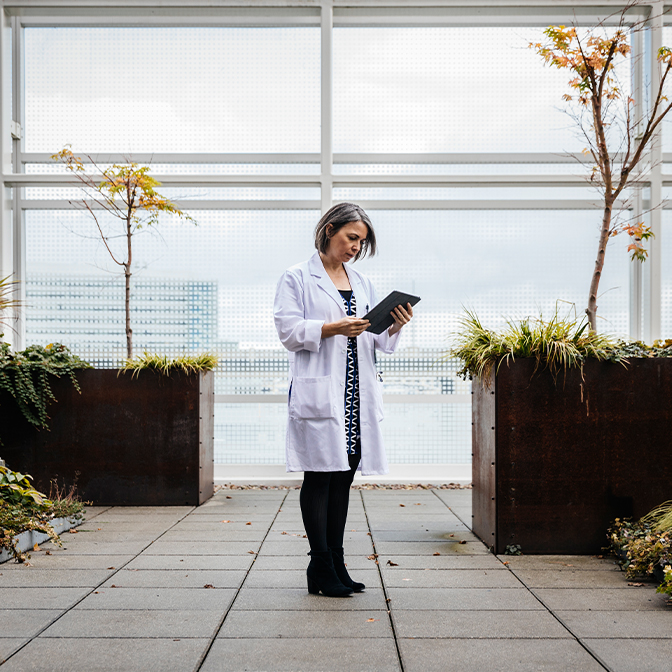 Female doctor using digital tablet while standing on rooftop of hospital